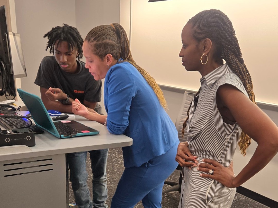 Denise Smith and Dr. Katherine Sudduth coaching a student at a laptop